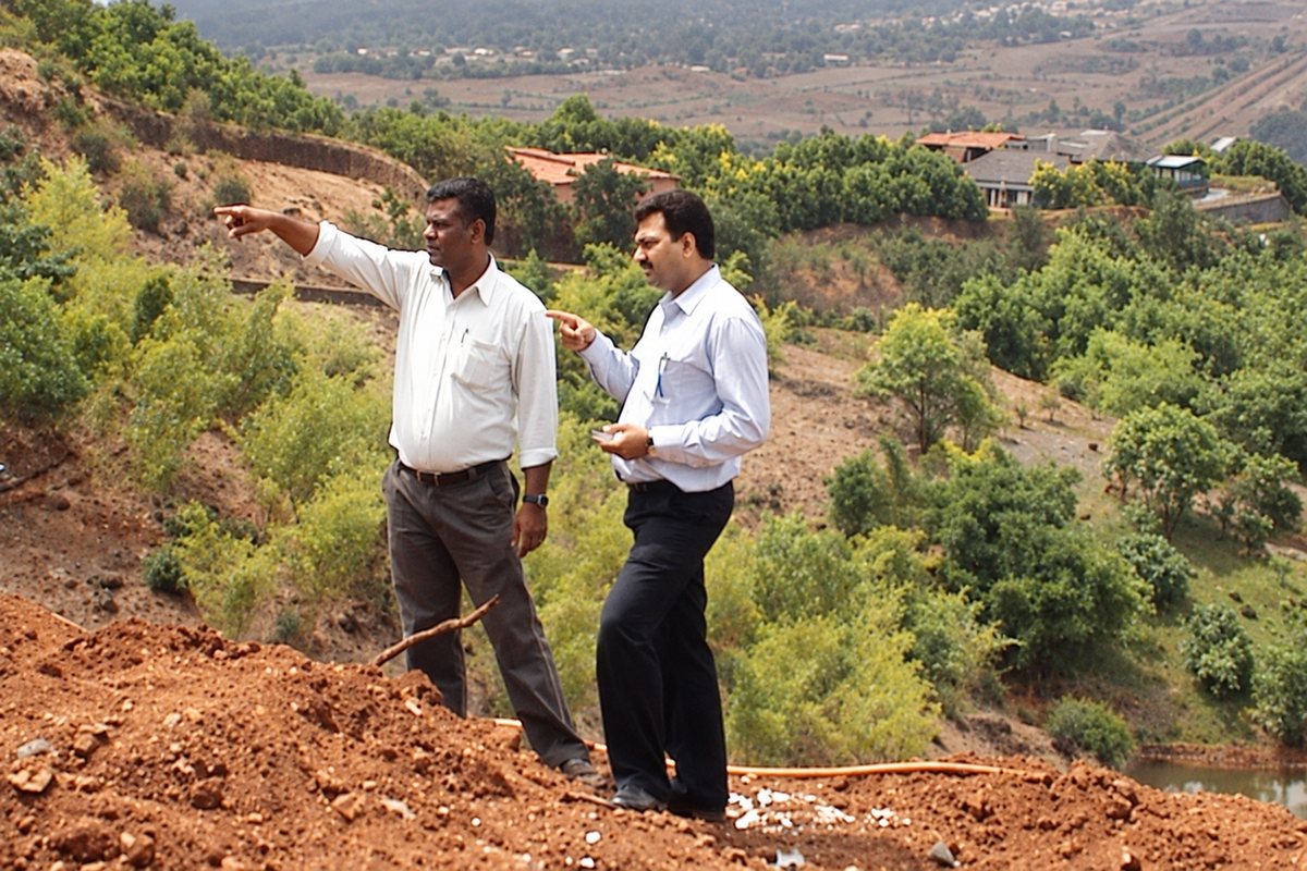 Two people evaluating an open plot of land before purchase